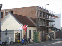 907599 Gezicht op de bouw van een nieuw appartementengebouw met een fietsenwinkel van rijwielhandel Huijsen Tweewielers ...